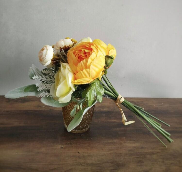 Ramo de flor artificial, en un estilo romántico de tonos suaves, tallos atados dando forma a un bouquet.